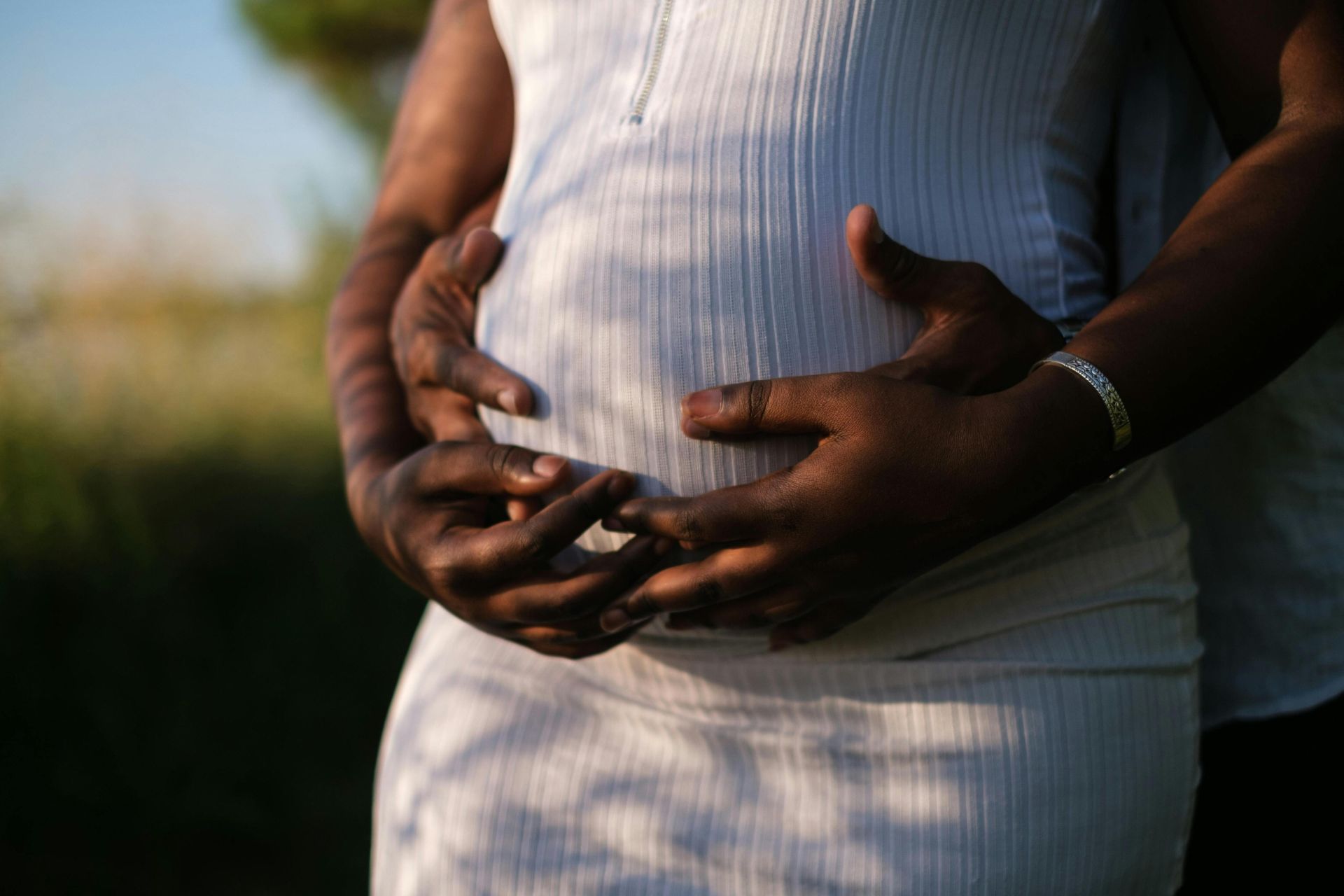 Couple embracing tenderly over a pregnant belly, symbolizing love and togetherness.